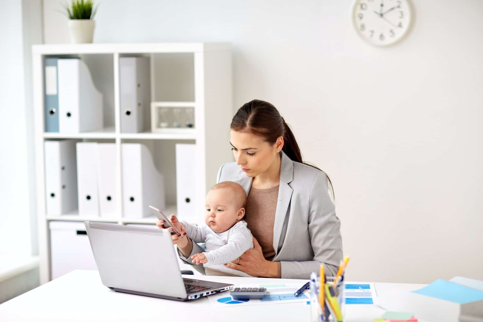 businesswoman with baby and smartphone at office