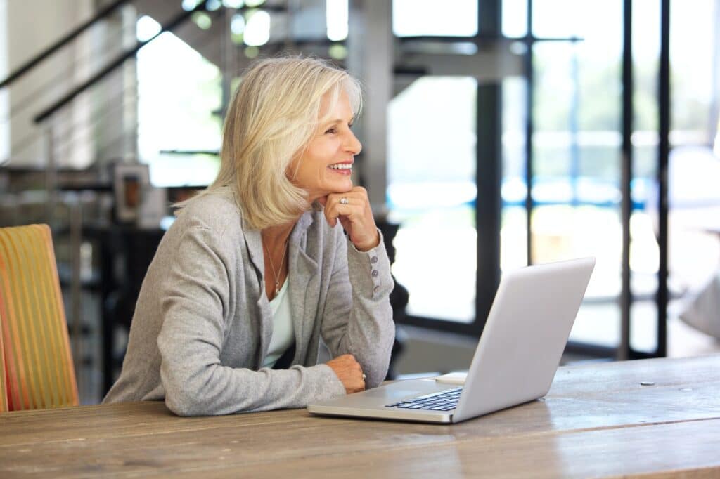 smiling older woman working laptop computer indoors