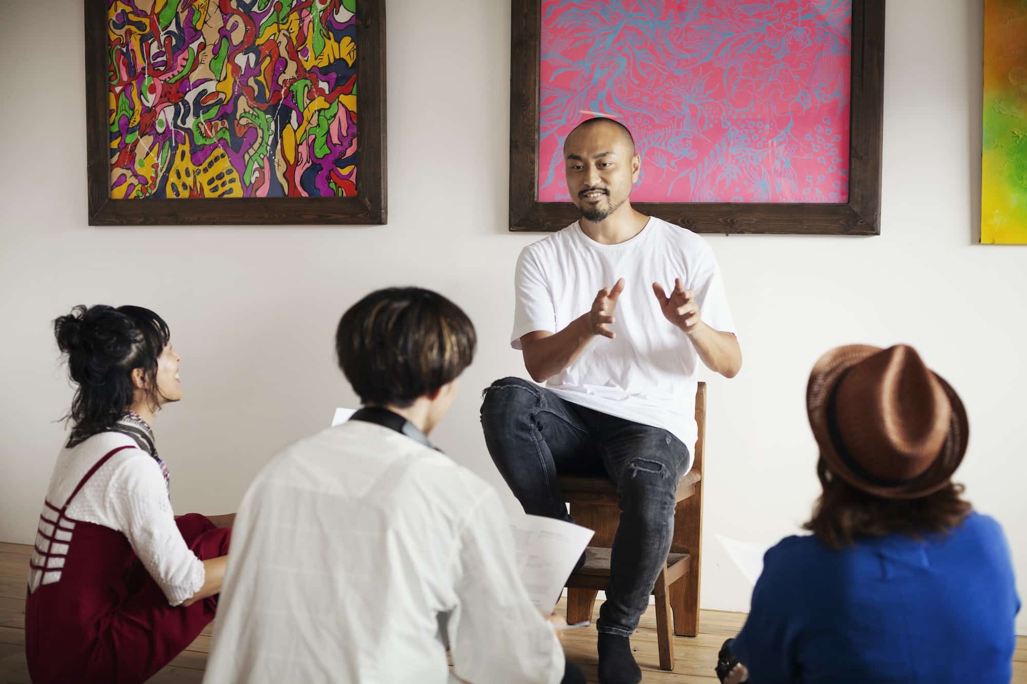 Group of Japanese men and women sitting in art gallery, holding a discussion.