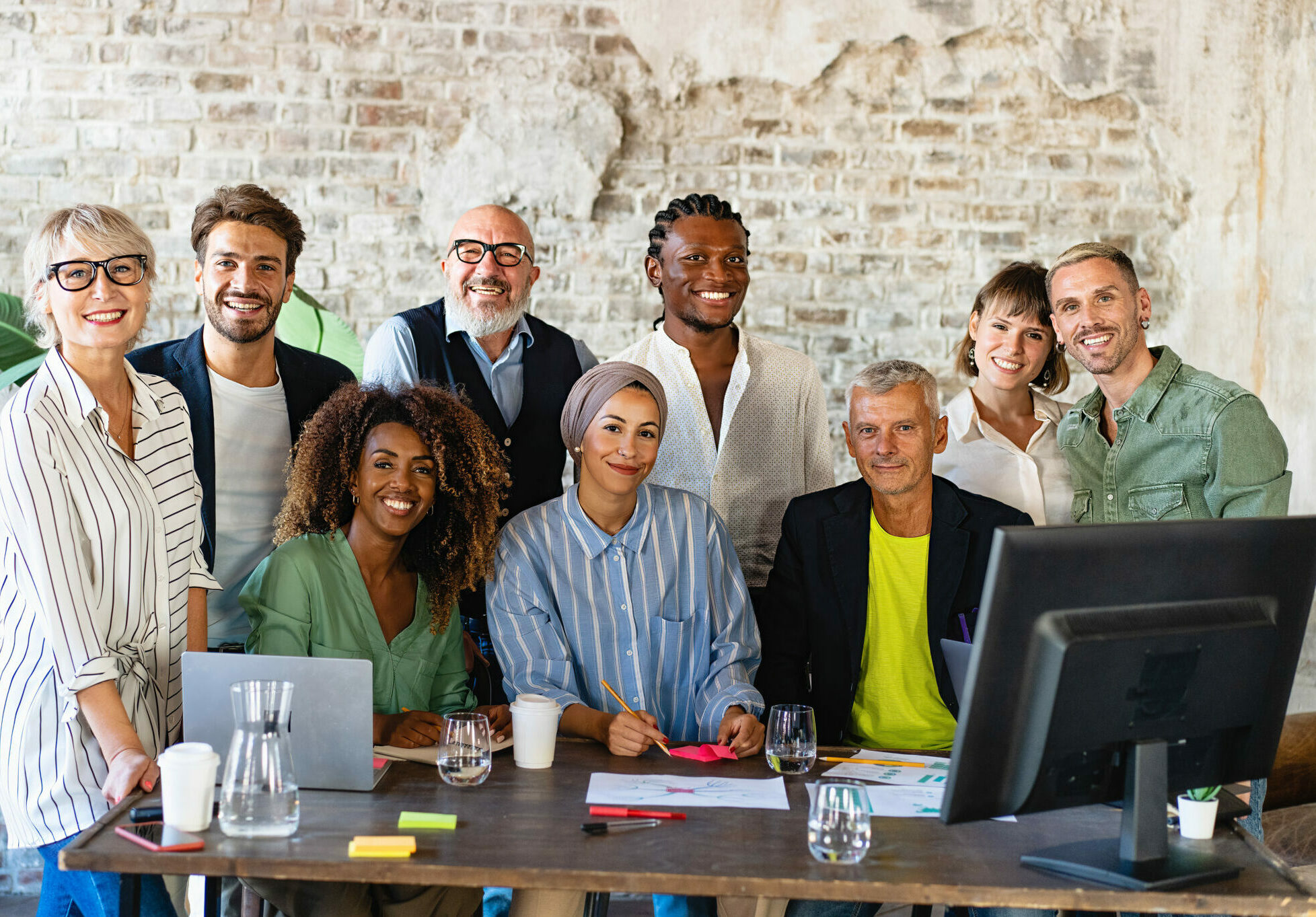 Portrait of successful group of multiethnic business people at modern office looking at camera. Portrait of happy creative team of satisfied businesspeople standing as a team. Multiracial group of people smiling.