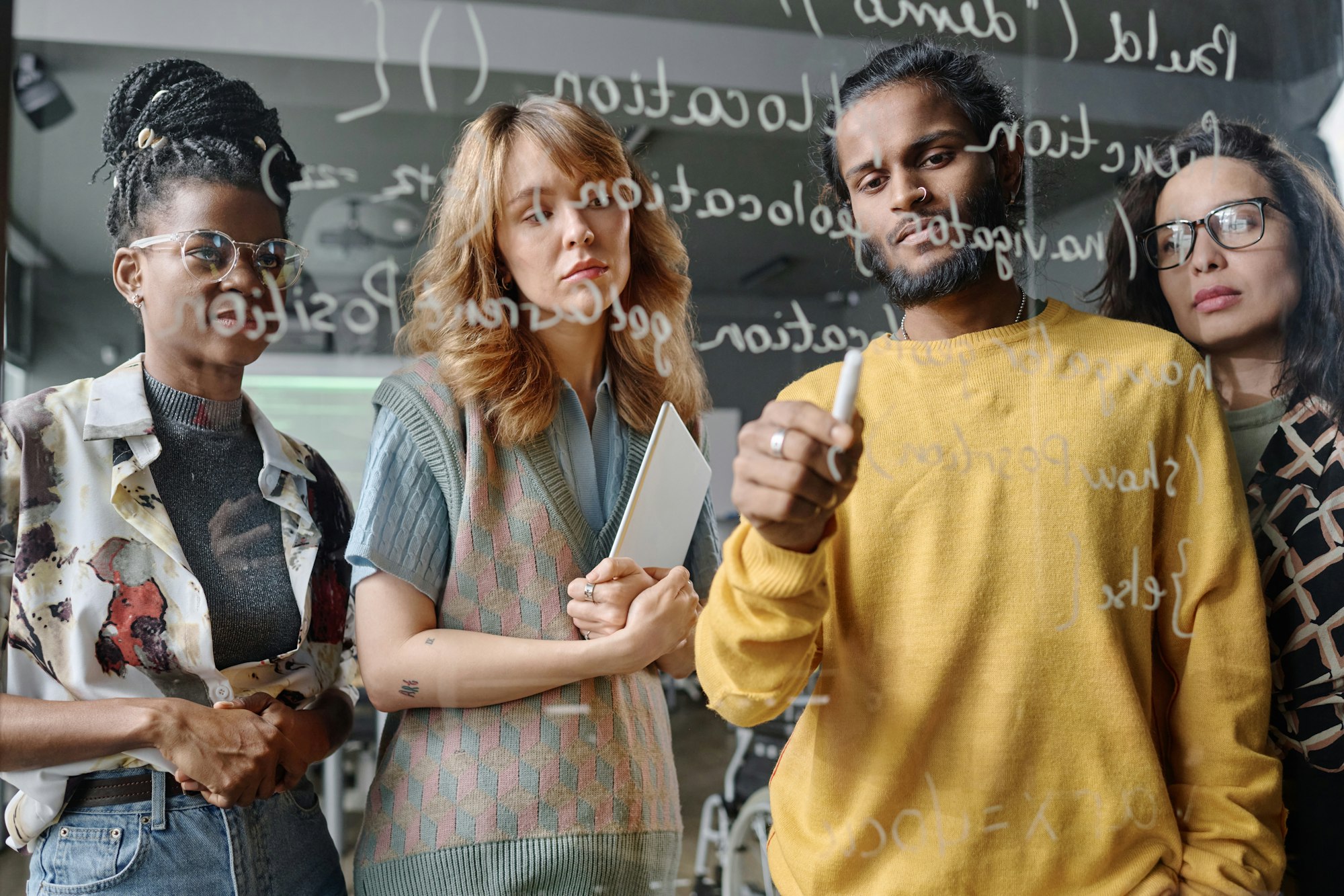 Multi-Ethnic Group of Young Office Workers Writing Code on Glass Wall